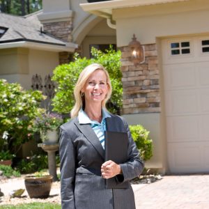 Professional real estate agent in business suit standing outside house.